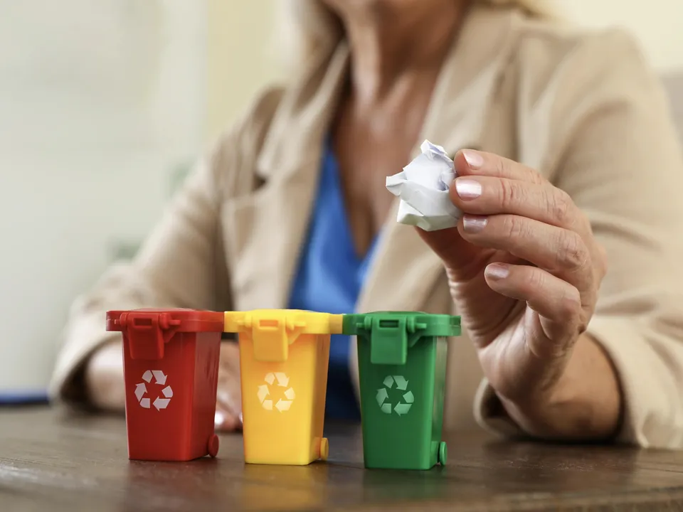 une salariée jette un papier dans une poubelle de recyclage